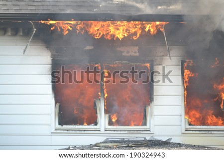 Flames are evident through the windows of a burning house during a training fire