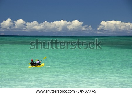 Father and son kayaking  on clear ocean water.