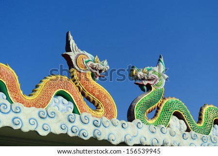 Twin dragons statue on the roof of Chinese temple with blue sky