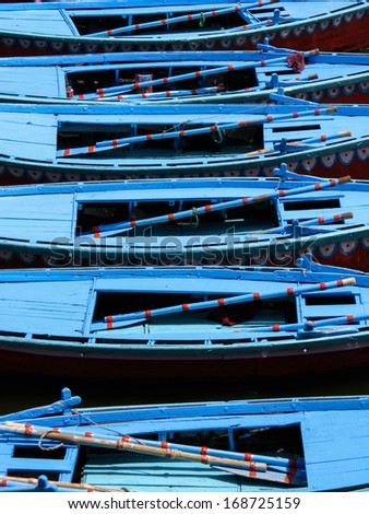 Brightly colored row boats lined up on the Ganges river in Varanasi, Uttar Pradesh, India.