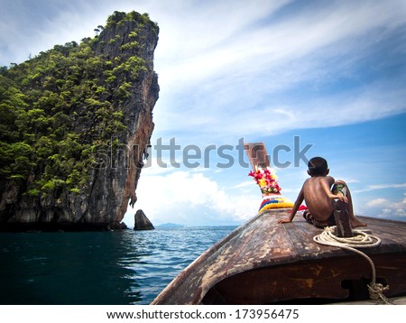 Koh Phi Phi, Thailand - May 09, 2013: Boy on traditional Thai long tail boat on the way to famous Maya Bay, Koh Phi Phi Island, Thailand.