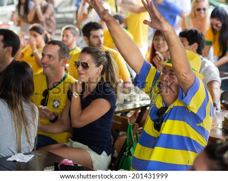 SALVADOR, BAHIA, BRAZIL - JUNE 28, 2014: Cheerful Brazil fans watching World Cup football match on TV at a bar in Salvador, Bahia, Brazil, on June 28, 2014.