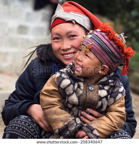 Happy Hmong woman and child smiling, sitting outside their house at Giang Ta Chai village near the hill town of Sapa, Lao Cai Province, North Vietnam.