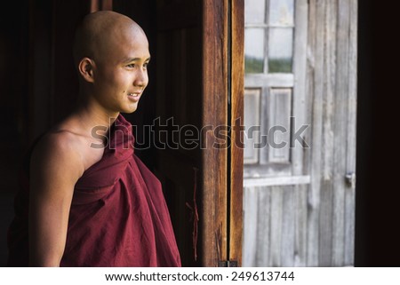 Inle Lake, Myanmar - March 23, 2014: Happy novice Buddhist monk looking out the window at Indein village monastery in Inle Lake, Shan State, Myanmar (Burma).