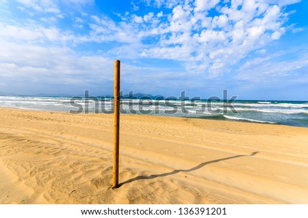 Wooden pole sign sandy beach white clouds sea blue sky, Can Picafort, Majorca island, Spain