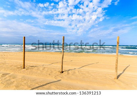 Wooden pole sign sandy beach white clouds sea blue sky, Can Picafort, Majorca island, Spain