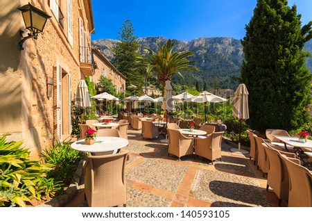 Sunny terrace table chair restaurant hotel mountains view palm tree, Deia village, Majorca island