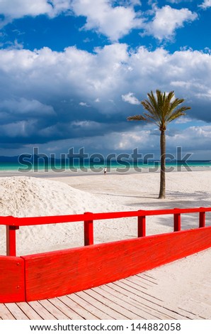 Red wooden footbridge walkway beach sea white clouds blue sky palm tree, Alcudia, Majorca island, Spain