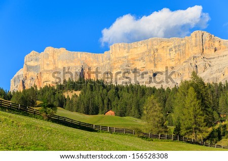 Green pasture meadow wooden hut with Dolomiti Mountains in the background, La Villa, Trentino Alta Badia, Italy