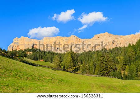 Green pasture meadow wooden hut with Dolomiti Mountains in the background, La Villa, Trentino Alta Badia, Italy