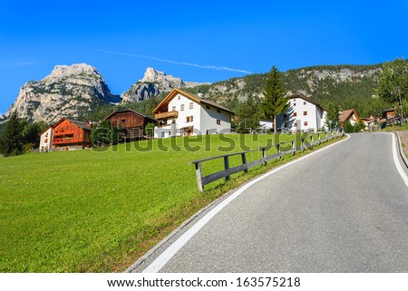Green meadow with houses and road in alpine village La Villa, Dolomites Mountains, Italy