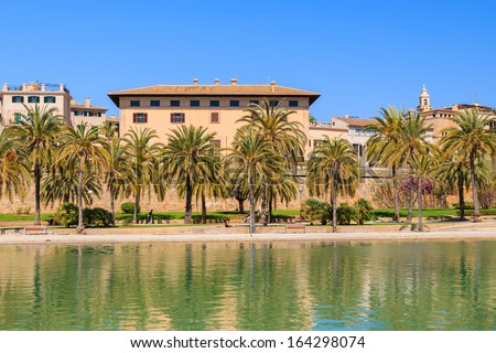 Reflection in lake of palace building near La Seu Cathedral  in Palma de Majorca with palm trees in front, Spain