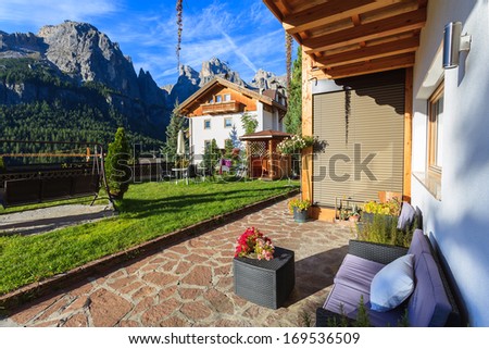 COLFOSCO, DOLOMITES, ITALY - SEPTEMBER 25, 2013: couch and coffee table on sunny patio of alpine house with beautiful mountain view and garden on  September 25, 2013 in Colfosco village, Italy.