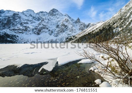 Reflection of Mieguszowieckie peaks in partly frozen Morskie Oko lake in winter season, High Tatra Mountains, Poland