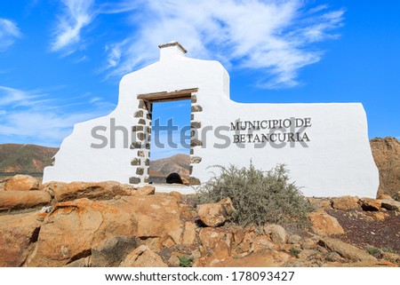 Traditional municipality sign (white arch gate) near Betancuria village with desert landscape in the background, Fuerteventura, Canary Islands, Spain