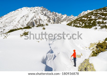 Young woman climber with ice-axe in 5 lakes valley in winter scenery, High Tatra Mountains, Poland