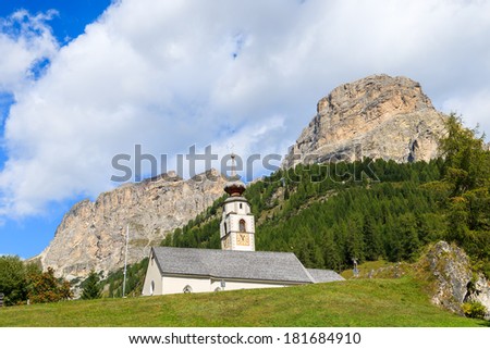 Church building in alpine village on sunny summer day, Colfosco, The Dolomites Mountains, Italy