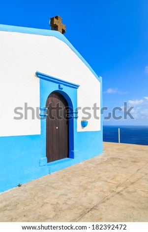 White small church building with sunny blue  sky and white clouds - view of Atlantic Ocean from tall cliff, Madeira island, Portugal