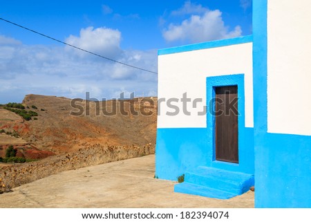 White small church building with sunny blue  sky and white clouds - view of mountain landscape, Madeira island, Portugal