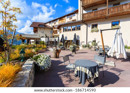 SAN CASSIANO, DOLOMITES, ITALY - SEPTEMBER 25, 2013: chairs with table on sunny terrace of alpine luxury restaurant and hotel on September 25, 2013 in San Cassiano village, Italy.