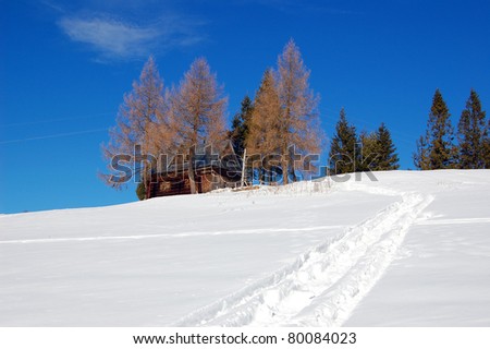 Path in snow with mountain hut in the distance in Gorce Mountains