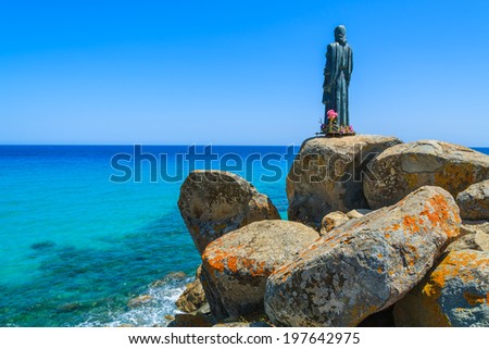Jesus Christ sculpture on rocks at Cala Sinzias beach and sea view, Sardinia island, Italy