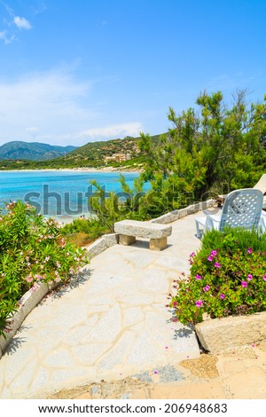 Sunchair on walkway to holiday house on coast of Sardinia island - view from promenade at Spiaggia del Riso beach, Italy