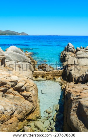 Sea water pool in rocks and crystal clear turquoise sea at Porto Giunco bay, Sardinia island, Italy