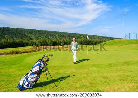 ARLAMOW GOLF COURSE, POLAND - AUG 3, 2014: mature man plays golf on sunny summer day in Arlamow Hotel. This luxury hotel was owned by Poland\'s government and is located in Bieszczady Mountains.