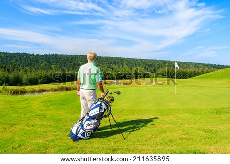 ARLAMOW GOLF COURSE, POLAND - AUG 3, 2014: mature man plays golf on sunny summer day in Arlamow Hotel. This luxury hotel was owned by Poland\'s government and is located in Bieszczady Mountains.