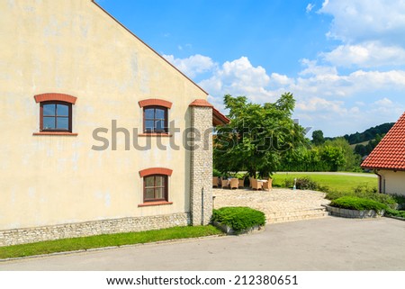 Historic building with chairs and tables on sunny terrace in Paczultowice village, Poland