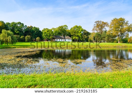 Lake in rural area of Radziejowice village with cottage house in background, Poland