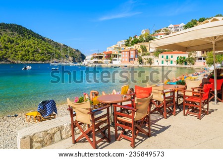 Tables with chairs in Greek tavern on beautiful beach in Assos village on Kefalonia island, Greece