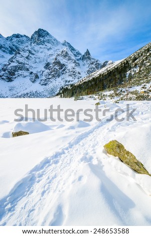 Path in snow on frozen Morskie Oko lake in winter, Tatra Mountains, Poland