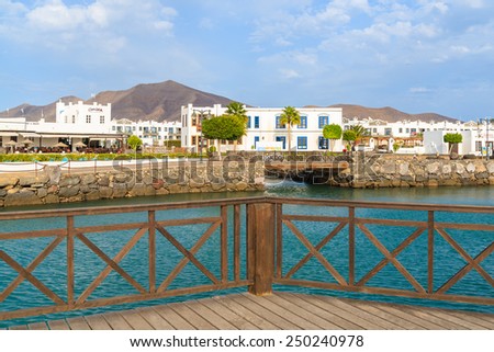 MARINA RUBICON, LANZAROTE ISLAND - JAN 11, 2015: Canarian buildings and footbridge in Rubicon port, Playa Blanca town. Canary Islands are popular holiday destination due to sunny tropical climate.