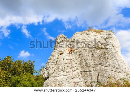 Climber on limestone rock in rural landscape near Krakow city, Poland