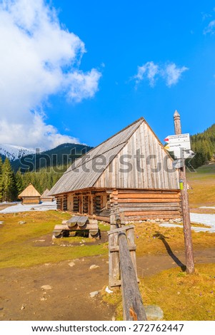 Wooden hut and mountain trail sign in Chocholowska valley in spring season, Tatra Mountains, Poland