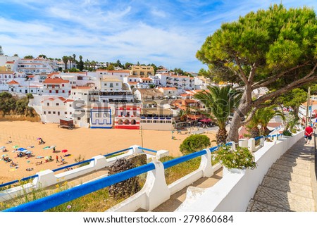 Promenade along street in Carvoeiro fishing village with view of colourful houses on beach, Algarve, Portugal