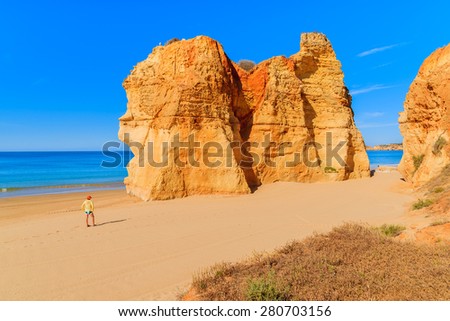 Tourist standing on beautiful Praia da Rocha beach, Algarve region, Portugal