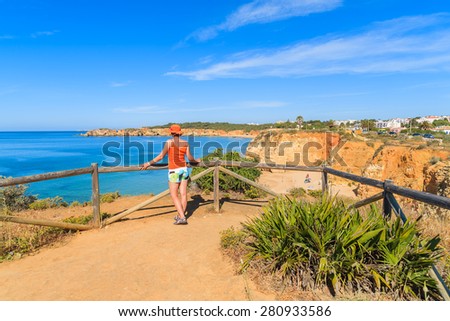 Young woman tourist standing on viewpoint and looking at beautiful Praia da Rocha beach, Portugal