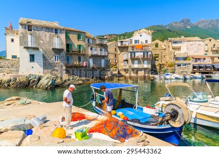 ERBALUNGA, CORSICA ISLAND - JUL 4, 2015: fishermen repair fishing nets in Erbalunga port on Cap Corse. This small village is known also as Bardo and is very popular tourist destination.