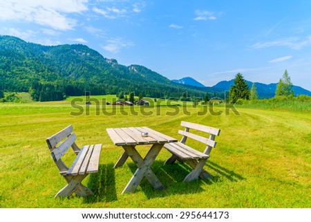 Wooden picnic table with benches on green meadow in summer landscape of Weissensee lake, Austria