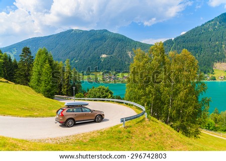 WEISSENSEE LAKE, AUSTRIA - JUL 6, 2015: Car on scenic mountain road driving along Weissensee lake in summer landscape of Carinthia region, Austria.