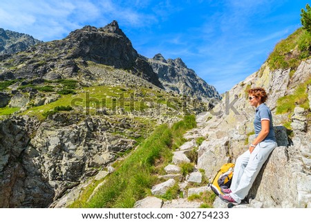 Young woman backpacker on mountain trail looking at Starolesna green valley in High Tatra Mountains, Slovakia