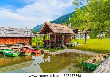 Fishing boats and wooden cabins on shore of Weissensee lake in summer landscape of Carinthia land, Austria