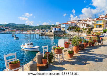 Flower pots on and view of fishing boats anchoring in Kokkari bay, Samos island, Greece