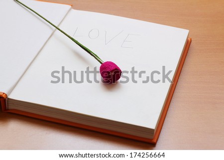purple flower put on the book on the wooden table
