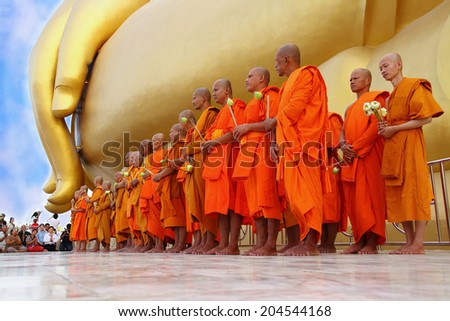 Ang Thong, Thailand-July 11,2014: Buddhists and monks walk with lighted candles clockwise round the temple, Asaha Puja Day and the beginning of Buddhist Lent, at Wat Muang- Ang Thong, Thailand.