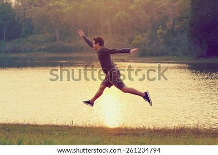 Jumps freedom, Asian man jumping on the river, during sunset, retro and vintage tone