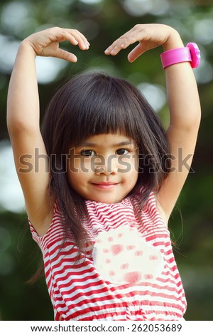 Portrait children, Sa Rang Hae Yo, Little asian girl doing heart shape in the park and look at camera